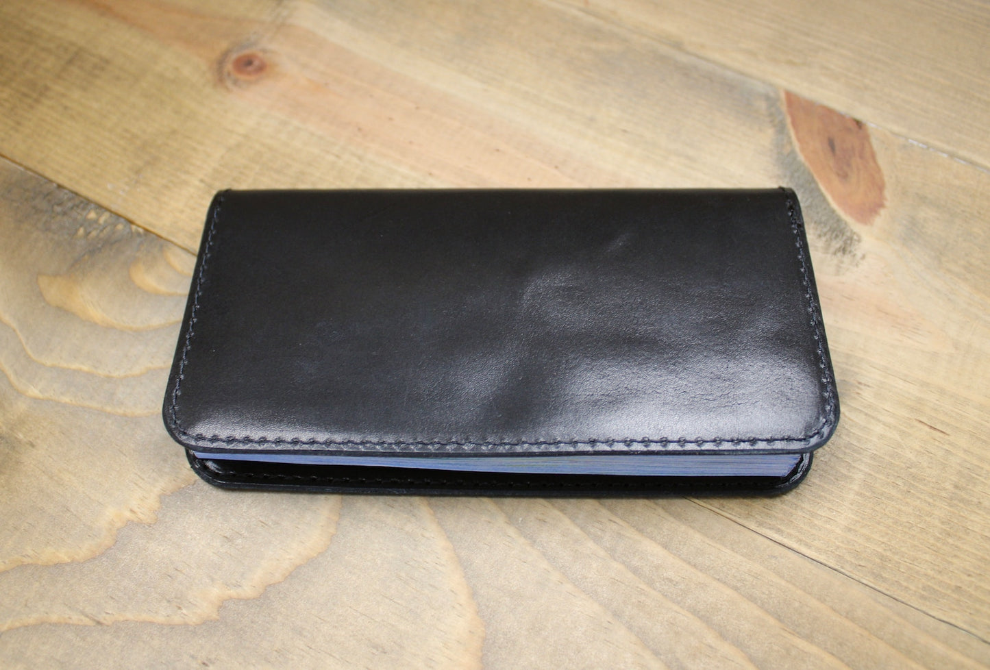 Elegant black leather checkbook holder with a sleek design, durable stitching, and spacious compartments for checks, cards, and essentials.