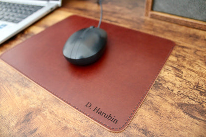 Cognac personalized leather mousepad with cream thread laser engraved with a name in the bottom right hand corner.